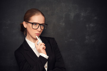 business woman teacher with glasses and a suit with chalk   at a