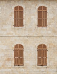 Old building wall with windows covered by wooden blinds