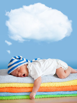 Yawning sleeping baby in funny hat with dream cloud for image or