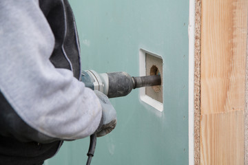 Bauarbeiter bohrt mit dem Bohrhammer in eine Fertigmauer