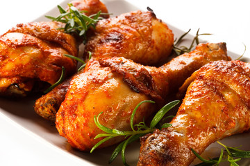 Grilled chicken legs and vegetables on white background