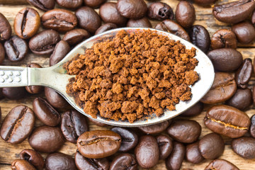 Coffee beans and ground coffee beans on a spoon.