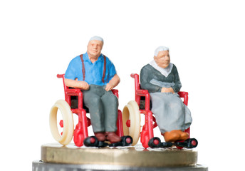 Altes Ehepaar im Rollstuhl auf einem Münzstapel