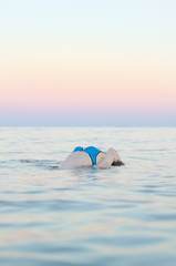 Woman in ocean at sunset.