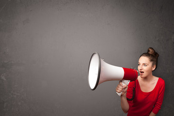 Girl shouting into megaphone on copy space background