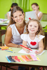 Erzieherin mit Mädchen beim Malen im Kindergarten