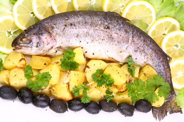Whole rainbow trout grilled with potatoes, lemons