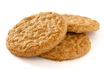 Detail of three crispy golden oat biscuits on white