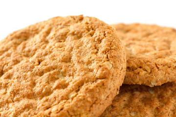 Detail of three crispy golden oat biscuits on white