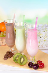 Milk shakes with fruits on table on light blue background