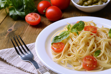 Delicious spaghetti with tomatoes on plate on table close-up