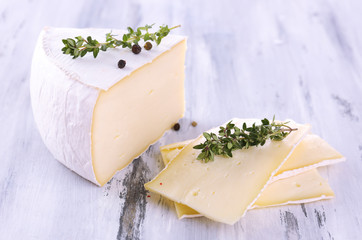 Tasty Camembert cheese with spices, on wooden table