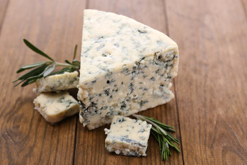 Tasty blue cheese with rosemary, on wooden table