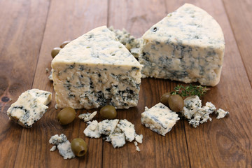 Tasty blue cheese with olives, on wooden table