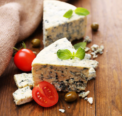 Tasty blue cheese with tomato, olives and basil, on wooden