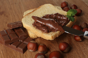 Bread with sweet chocolate hazelnut spread on wooden background
