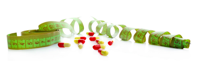 Measuring tape and pills, isolated on white. Dieting concept