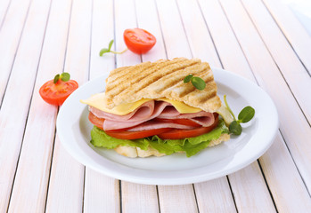Tasty sandwich with ham on wooden table