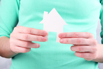 Little paper house in hand close-up, on light background