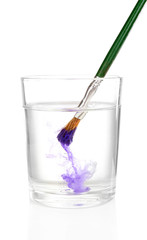 Brush with color paint in glass of water, isolated on white