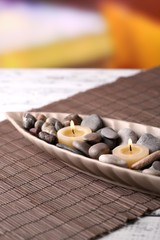Spa stones and candle in decorative bowl,