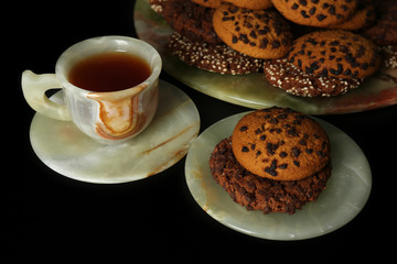 Cup of coffee with cookies on dark background