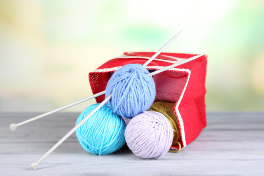Woolen balls of yarn in rustic craft bag, om wooden table,