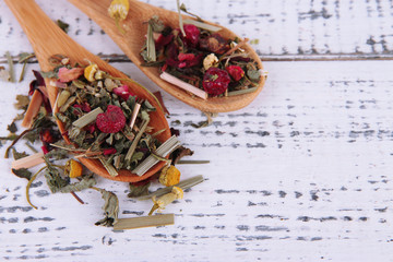 Aromatic dry tea in spoons on wooden background