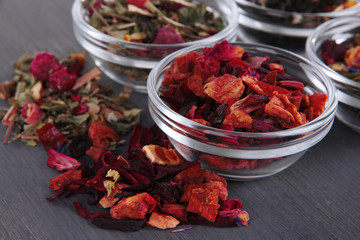 Aromatic dry tea in bowls on wooden background