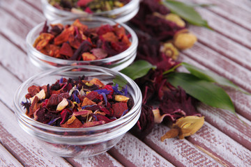 Aromatic dry tea in bowls on wooden background