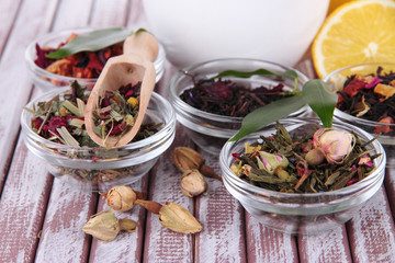Aromatic dry tea in bowls on wooden background
