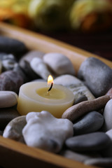 Fototapeta na wymiar Wooden bowl with spa stones and candles