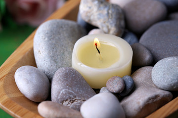 Wooden bowl with spa stones and candles