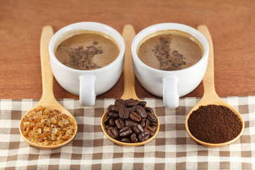 cup of coffee with coffee beans and sugar in wooden spoon