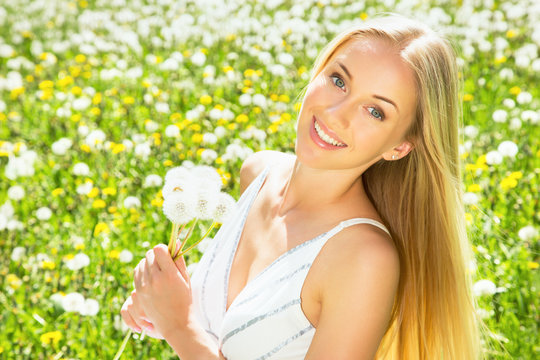 Beautiful young woman among dandelions