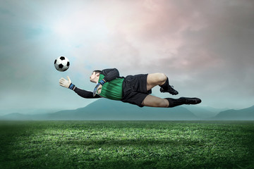 Goalkeeper with ball in action outdoors.