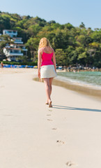  woman walks along seashore. Focus on footprints