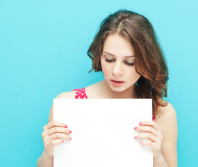 Fototapeta premium beautiful girl with a white sheet of paper on a blue background
