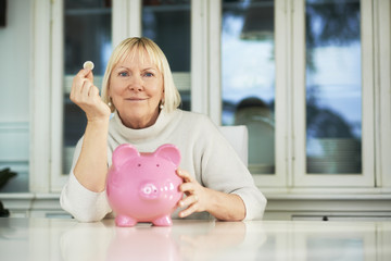 Old woman showing piggybank and euro coin