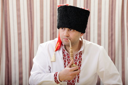 Ukrainian Cossack in national dress smokes a pipe
