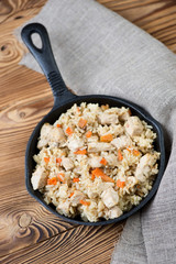 Pilaf with chicken in a frying pan, vertical shot, above view