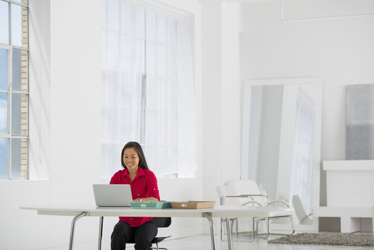 Light And Airy Working Environment. A Woman Seated Using A Laptop. 