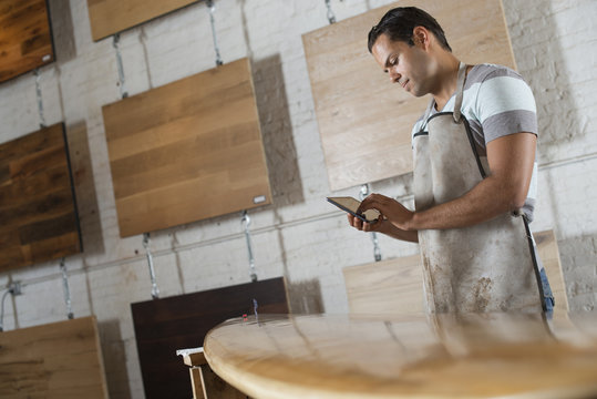 A Young Man In A Workshop. Using A Digital Tablet To Keep Records And Photograph Objects.