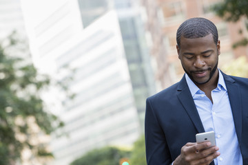 Summer. A Man In A Blue Jacket And Open Collared Shirt Using A Smart Phone. 