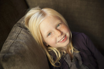 A Girl Sitting On A Couch, Smiling At The Camera. 