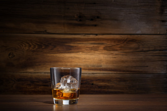 glass of whiskey with ice on a wooden background