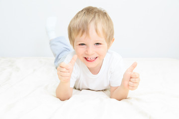 Fototapeta premium happy little boy with thumbs up on white