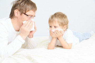 father and son wiping nose