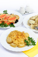 White table with food of meat, salmon rolls and dumplings.