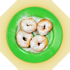 Green dish with donuts, coated with powdered sugar